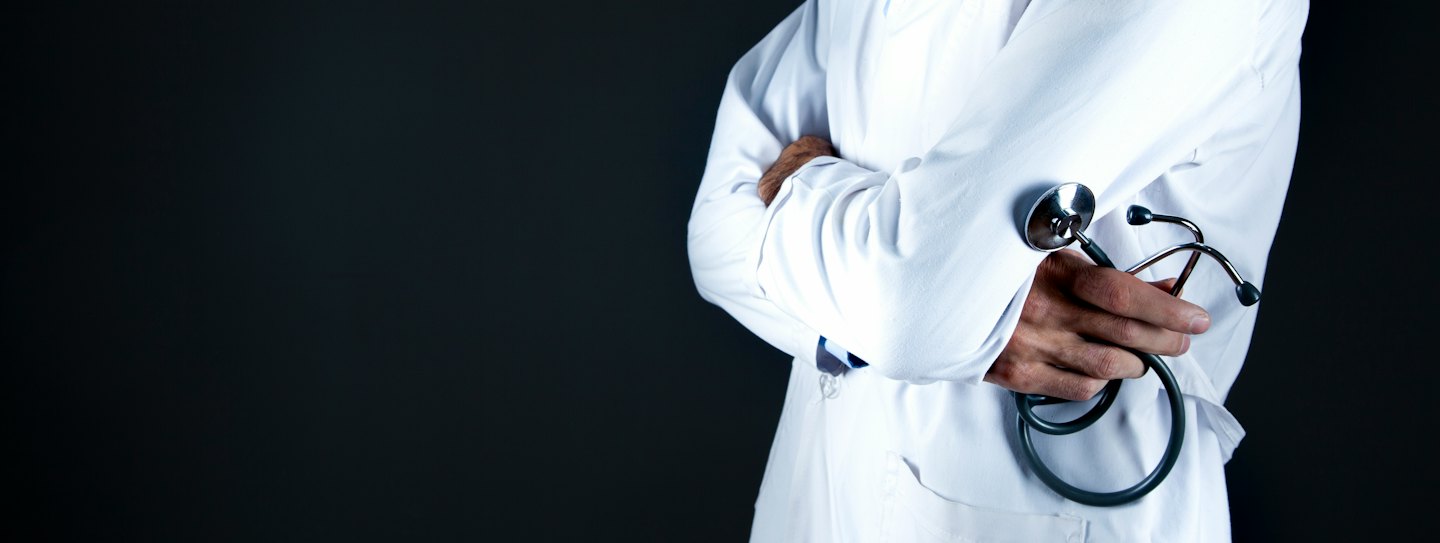 Medical professional in lab coat holding a stethoscope.